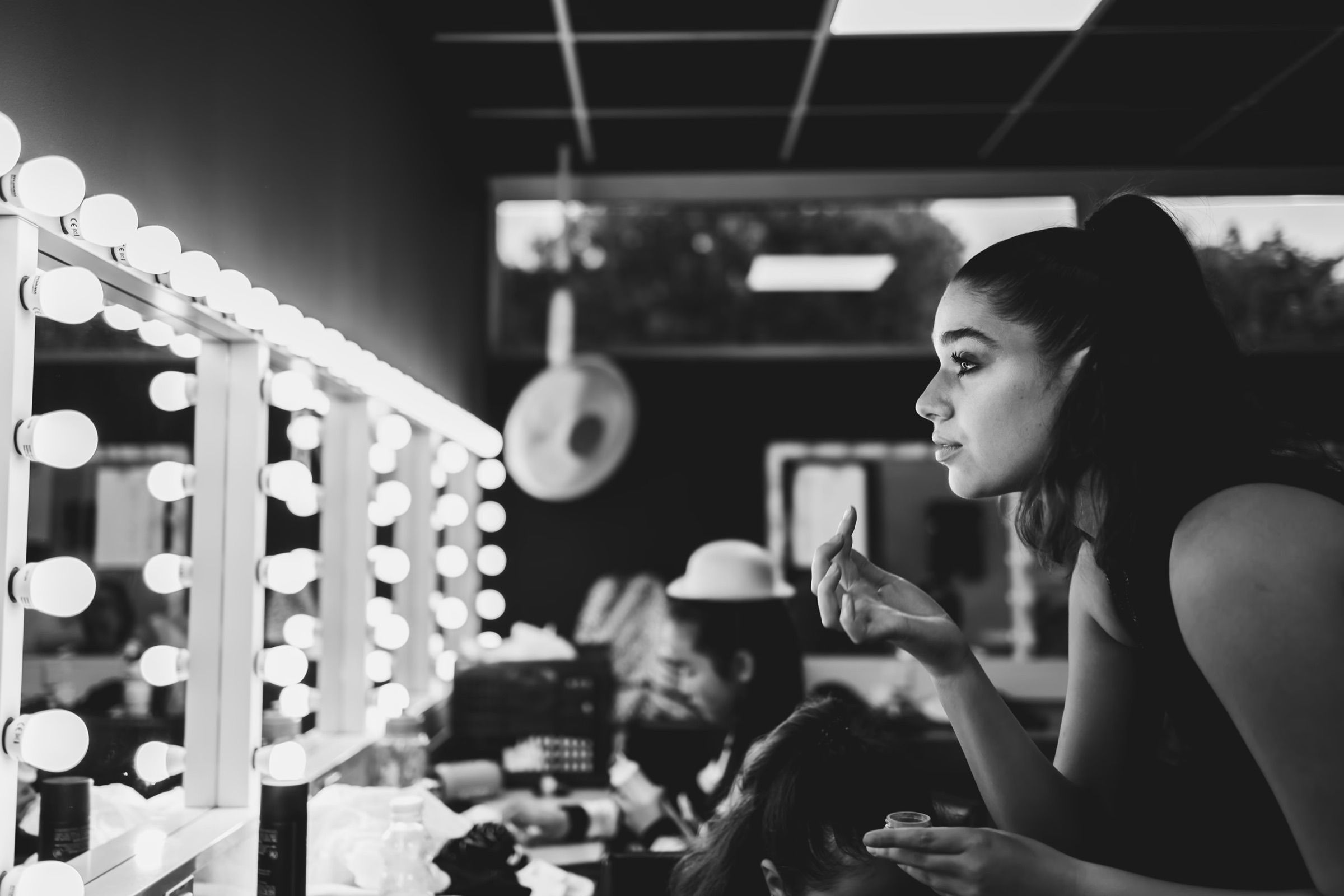 Black and white: a dancer does her make-up at a dressing-room mirror ringed with bulbs.